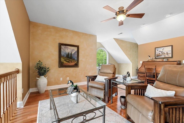 living area with a ceiling fan, light wood-type flooring, baseboards, and lofted ceiling