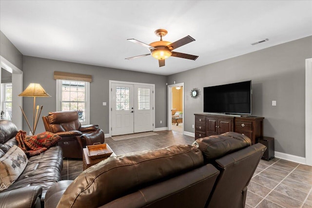 living area featuring ceiling fan, baseboards, and tile patterned flooring