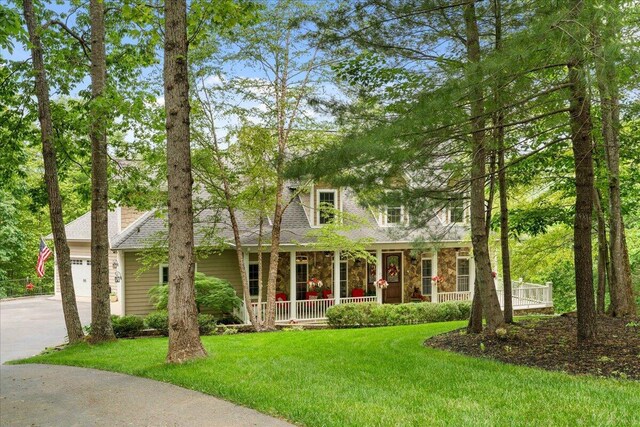 view of front of property with a porch, a front lawn, a garage, driveway, and stone siding