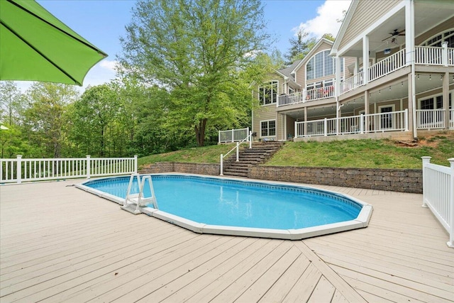 outdoor pool featuring a deck, ceiling fan, and stairway