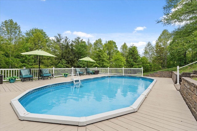 view of swimming pool featuring a deck and view of wooded area