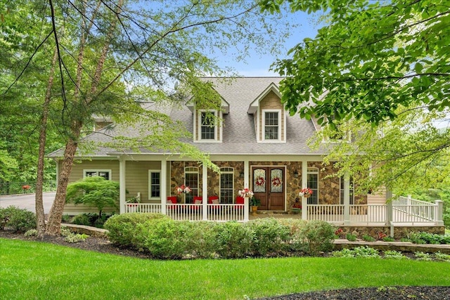 view of front of property with stone siding, a porch, a front yard, and a shingled roof