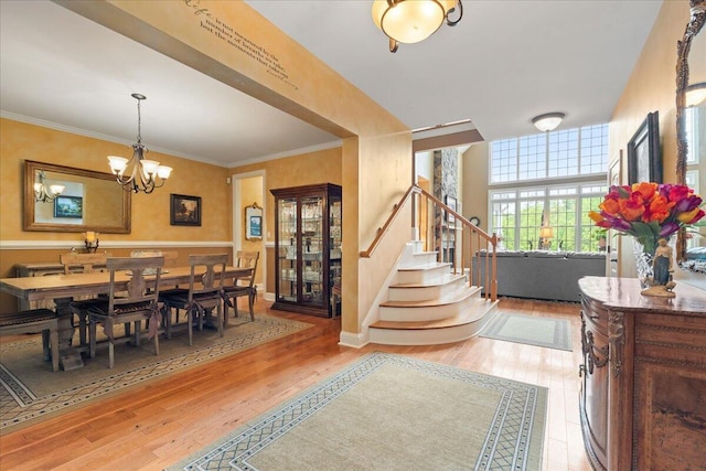 dining room with stairway, light wood-style flooring, a chandelier, and ornamental molding
