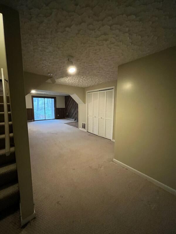 below grade area featuring carpet flooring, baseboards, and a textured ceiling