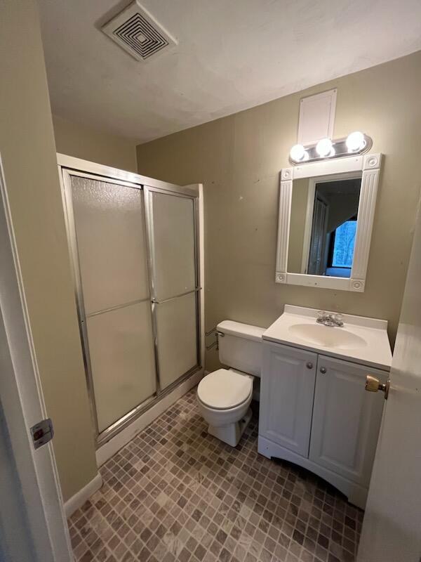 full bathroom with a stall shower, toilet, vanity, and baseboards
