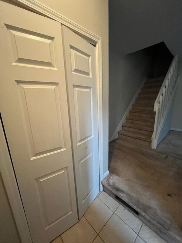 stairs with tile patterned flooring, carpet floors, and baseboards
