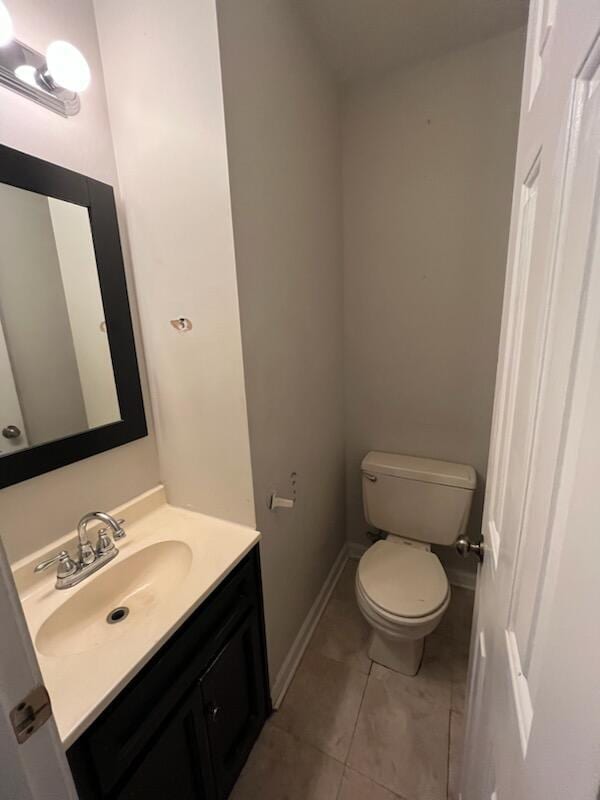 bathroom featuring toilet, vanity, tile patterned floors, and baseboards