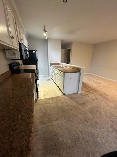 kitchen featuring electric stove, stainless steel microwave, white dishwasher, a sink, and dark countertops