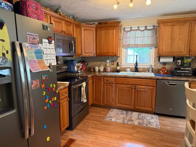 1134 Coolbrook Rd, Bedford, VA 24523 - kitchen featuring stainless steel appliances, a sink, backsplash, brown cabinetry, and light wood finished floors