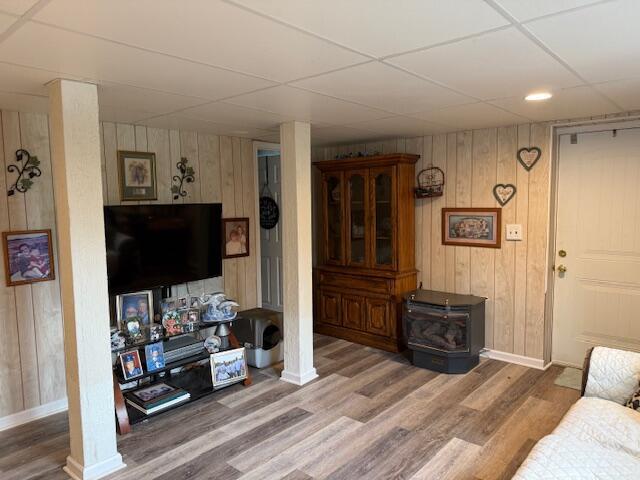 1134 Coolbrook Rd, Bedford, VA 24523 - living area featuring a wood stove, wood finished floors, baseboards, wood walls, and a drop ceiling