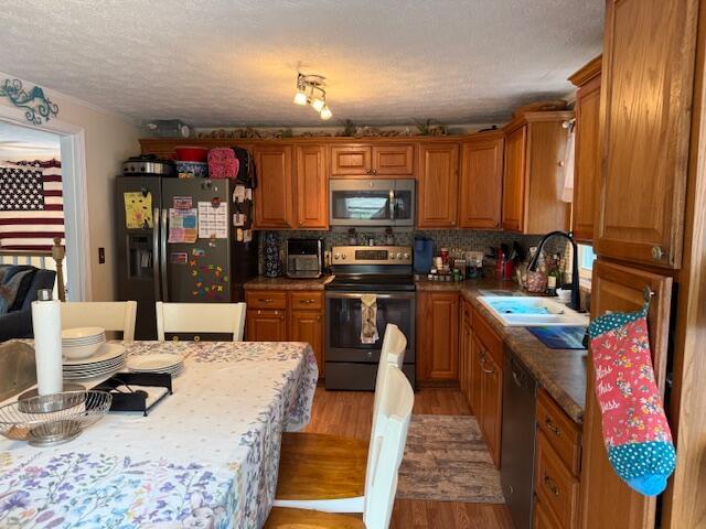 1134 Coolbrook Rd, Bedford, VA 24523 - kitchen featuring appliances with stainless steel finishes, a sink, light wood-style flooring, a textured ceiling, and brown cabinets