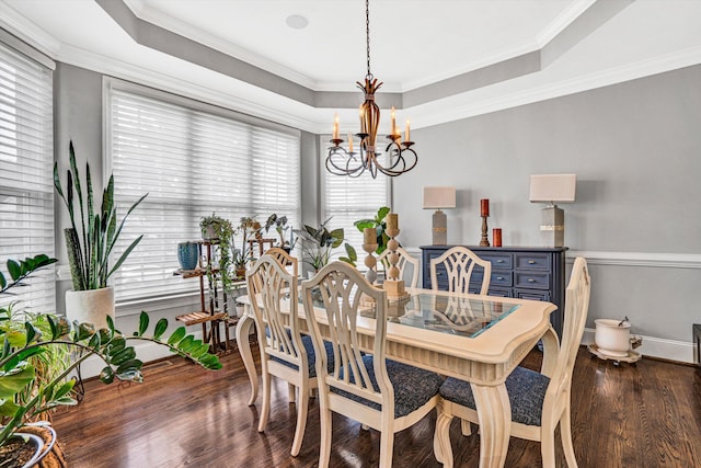 dining room with a chandelier, wood finished floors, baseboards, ornamental molding, and a raised ceiling
