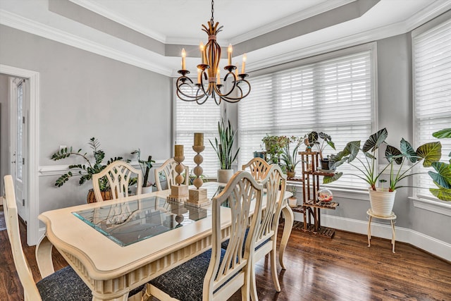 dining room with a chandelier, wood finished floors, crown molding, baseboards, and a raised ceiling