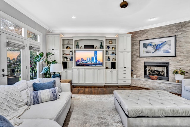 living area with crown molding, dark wood-style flooring, a stone fireplace, and recessed lighting