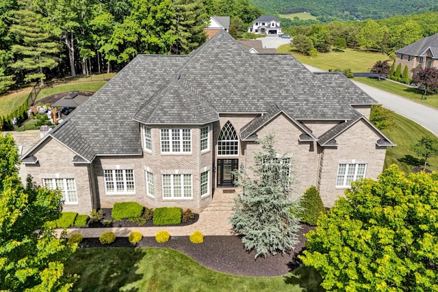view of front facade with brick siding and roof with shingles