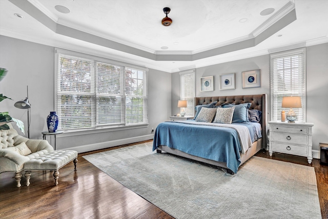 bedroom with a raised ceiling, crown molding, wood finished floors, and multiple windows