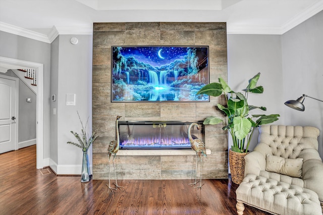 living room with wood finished floors, stairs, crown molding, baseboards, and a large fireplace
