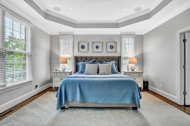 bedroom featuring wood finished floors, a raised ceiling, multiple windows, crown molding, and recessed lighting