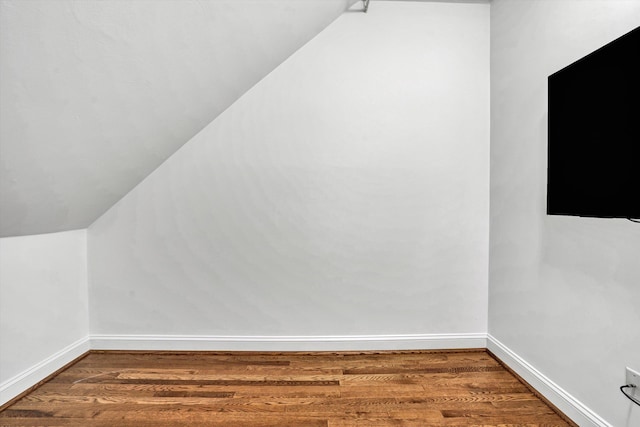 additional living space featuring wood finished floors, lofted ceiling, and baseboards