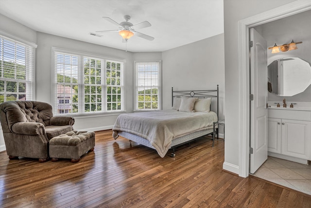 bedroom with wood-type flooring, baseboards, ceiling fan, and connected bathroom