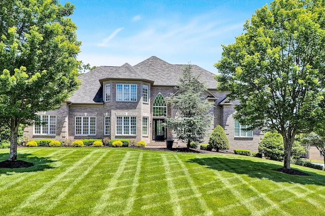 french country style house featuring a front yard and brick siding