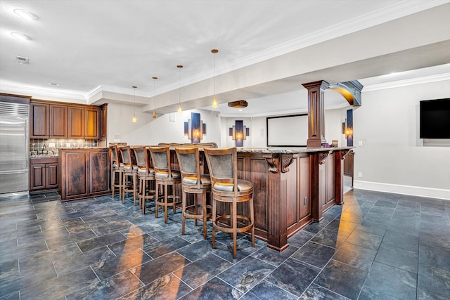 indoor bar featuring built in refrigerator, baseboards, hanging light fixtures, crown molding, and tasteful backsplash