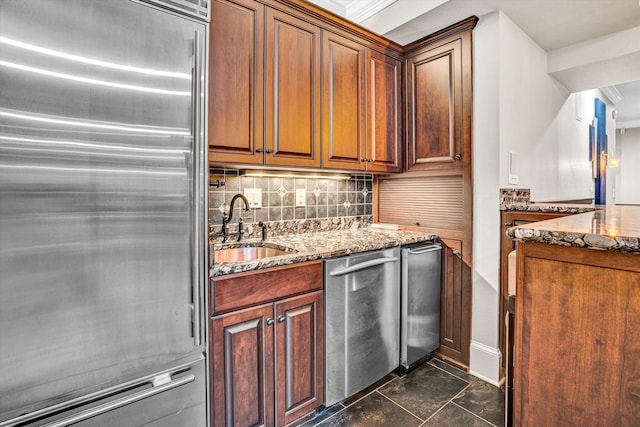 kitchen with stainless steel appliances, a sink, stone counters, decorative backsplash, and dark marble finish floors