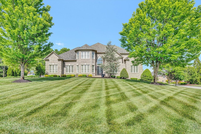 french provincial home featuring a front yard and brick siding