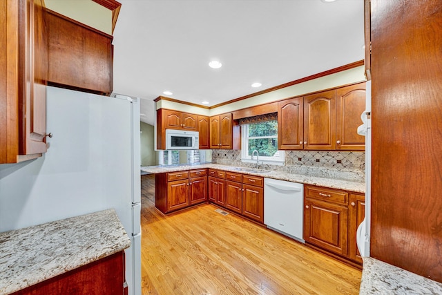 kitchen with white appliances, a sink, light wood-type flooring, crown molding, and tasteful backsplash