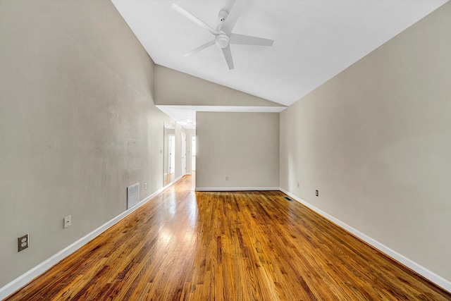 spare room with lofted ceiling, a ceiling fan, wood finished floors, and baseboards
