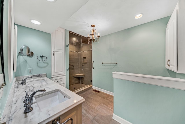 bathroom featuring a shower stall, double vanity, baseboards, a chandelier, and recessed lighting