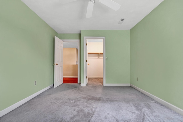 unfurnished bedroom with carpet floors, a spacious closet, baseboards, and a closet