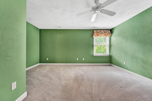 carpeted spare room featuring baseboards and ceiling fan