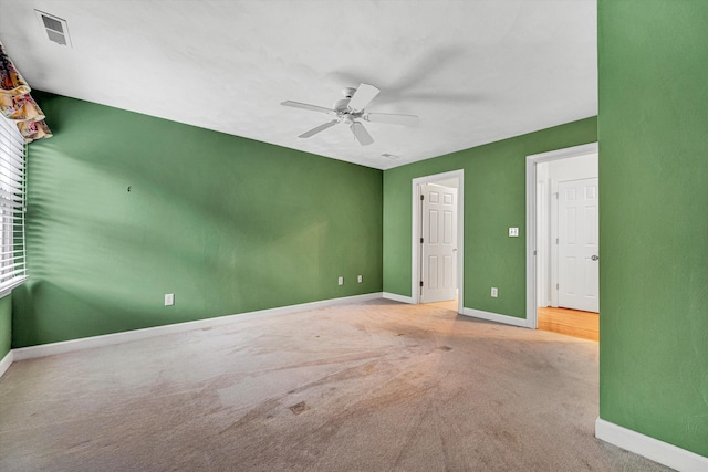 carpeted empty room with ceiling fan and baseboards