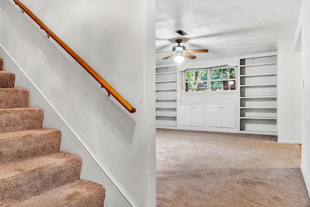 staircase featuring ceiling fan, carpet floors, and built in features