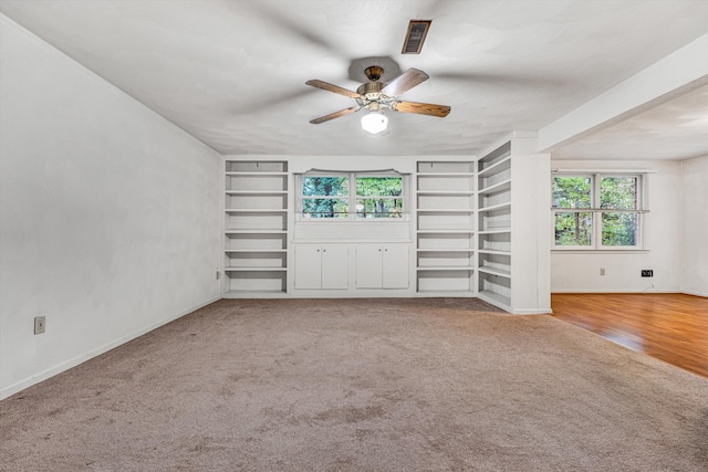 unfurnished living room featuring plenty of natural light, carpet floors, ceiling fan, and built in features