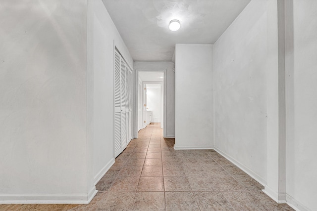 corridor with light tile patterned flooring and baseboards