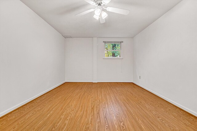 spare room featuring light wood-style floors, baseboards, a ceiling fan, and lofted ceiling