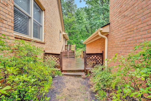 view of home's exterior with a wooden deck and brick siding
