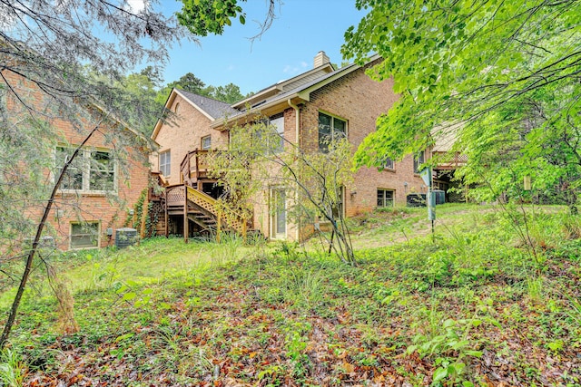 rear view of property with stairway, brick siding, a chimney, and a deck