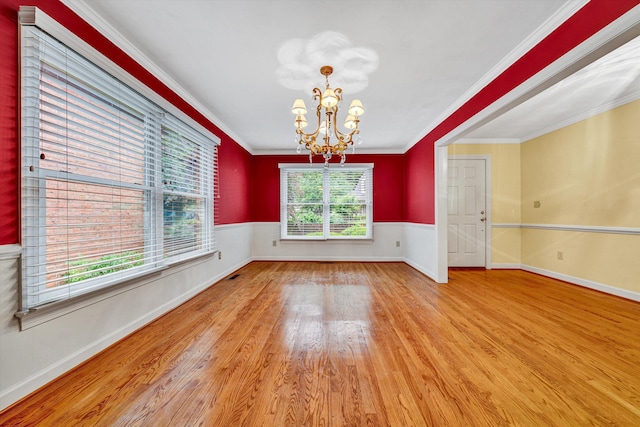 spare room with wood finished floors, a chandelier, crown molding, and baseboards