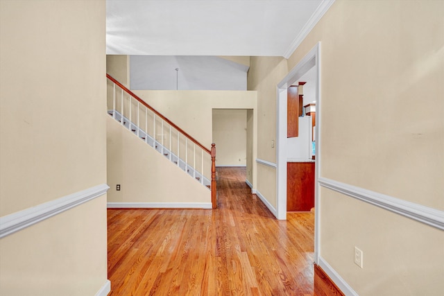 entrance foyer with wood finished floors, crown molding, stairway, and baseboards