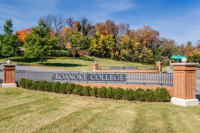 community / neighborhood sign featuring a yard and view of scattered trees