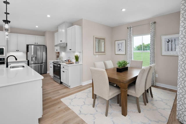 dining area with baseboards, light wood-style flooring, and recessed lighting