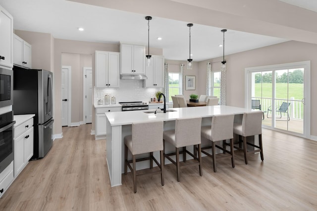 kitchen with a sink, light wood-type flooring, a kitchen bar, tasteful backsplash, and recessed lighting