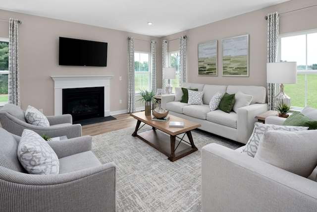 living room with healthy amount of natural light, light wood-type flooring, a fireplace with flush hearth, baseboards, and recessed lighting