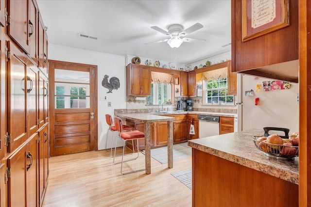 kitchen featuring white appliances, a sink, brown cabinets, light wood-style flooring, and ceiling fan