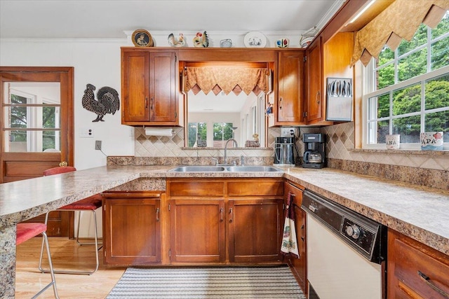 kitchen featuring dishwasher, a sink, healthy amount of natural light, brown cabinets, and ornamental molding