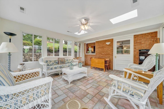 sunroom featuring a skylight and brick floors