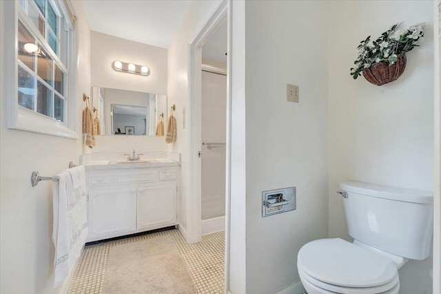 bathroom with vanity, toilet, a stall shower, and baseboards